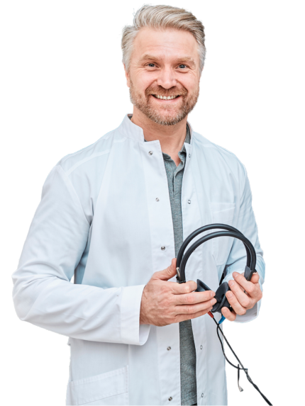 A photo of a dark-haired female audiologist in a white lab coat holding an otoscope with her arms crossed and smiling.